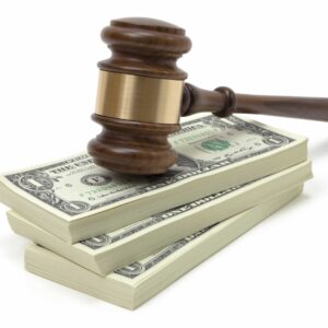 A judge's gavel resting on a pile of one-dollar bills