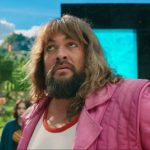 large bearded man with long hair in pink jacket and white scoop-neck t-shirt