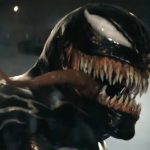 closeup of alien symbiote Venom facing camera with long tonge lolling out of a mouth lined with sharp teeth