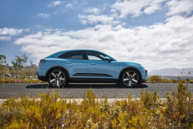 A Porsche Macan EV in profile with some vegetation in the foreground