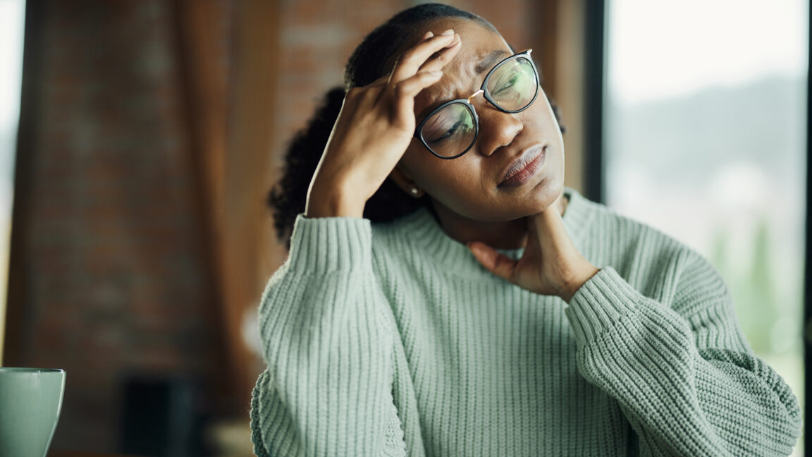 Displeased African American woman holding her head in pain.