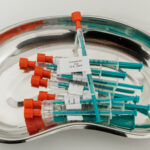 Syringes with drawn-up coronavirus vaccine lie in a bowl.