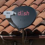 A satellite TV dish with the Dish logo on a roof.