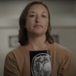 A woman holding an MRI displaying a brain tumor.