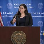 Colorado Secretary of State Jena Griswold speaks from behind a podium during a press conference.