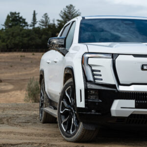 A white GMC Sierra EV Denali, seen from the front, but only half the truck is in frame.