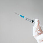 Conceptual image of a gloved hand holding a syringe.