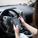 A woman is driving with a cell phone (posed scene)