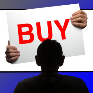 Someone watching a TV that has hands coming out of it which are holding a sign that says "BUY."