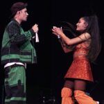 Justin Bieber performs with Ariana Grande on a music festival stage. The singers are facing each other and holding microphones.