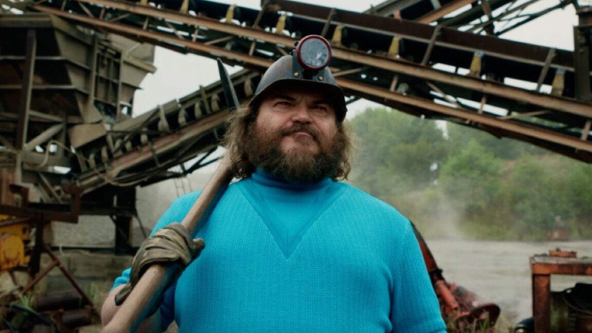 pudgy bearded man in turquoise tee and baseball cap with a a long handled tool resting on his shoulder.