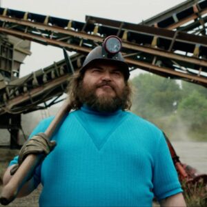 pudgy bearded man in turquoise tee and baseball cap with a a long handled tool resting on his shoulder.