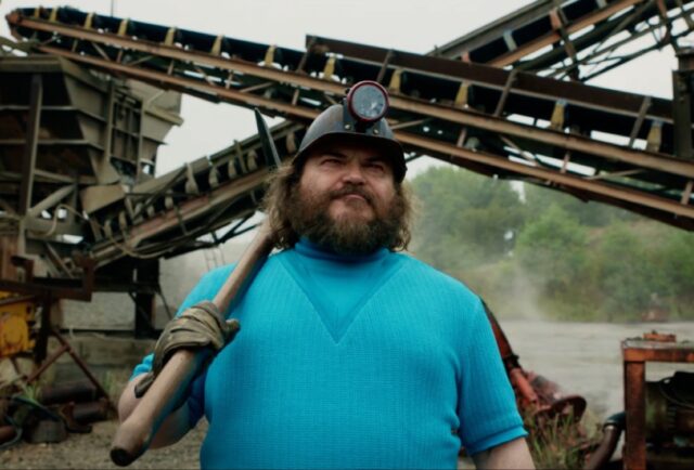 pudgy bearded man in turquoise tee and baseball cap with a a long handled tool resting on his shoulder.