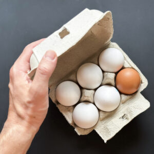 High angle view of hand opening eggs cardboard box