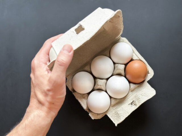 High angle view of hand opening eggs cardboard box