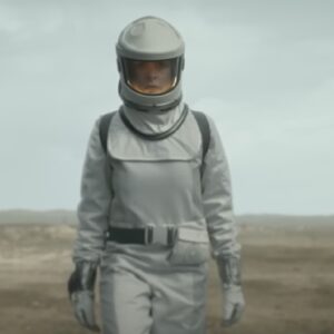 woman in white space suit walking across a desolate plain