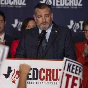 Ted Cruz stands in front of a microphone surrounded by supporters and Ted Cruz signs