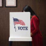 A photo of a person voting in a voting booth.