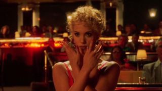 elizabeth berkley holding her hands in front of her face in a vegas restaurant in the movie showgirls