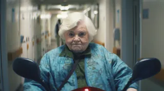 June Squibb as Thelma, riding a motorized scooter down a hospital hallway, in 'Thelma.'