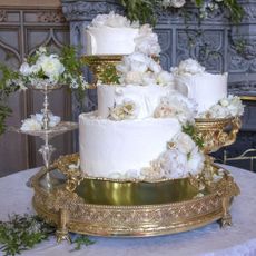 Meghan Markle and Prince Harry's white tiered wedding cake covered in flowers on a gold tiered stand 