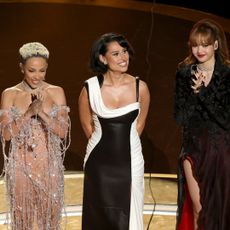 Doja Cat, RAYE, and LISA stand on stage at the 2025 Oscars.