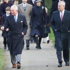 King Charles walking next to Prince Andrew wearing a long coat