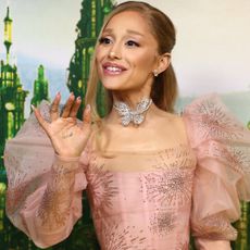 Ariana Grande on the Wicked red carpet wearing a butterfly necklace and a french manicure