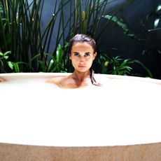 Attractive girl takes milk bath with milk.