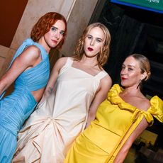 Three women with different colored hair and gowns pose.