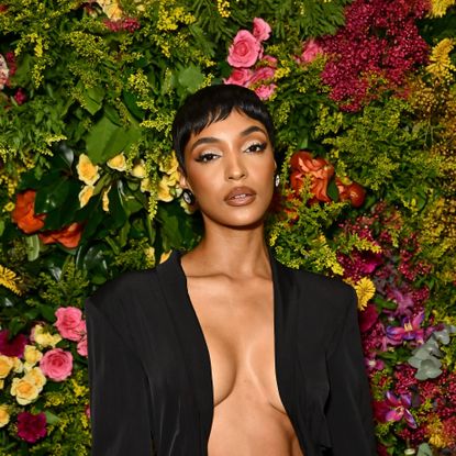 A model, Jourdan Dunn, stands in front of a wall of flowers showing off a new short haircut.