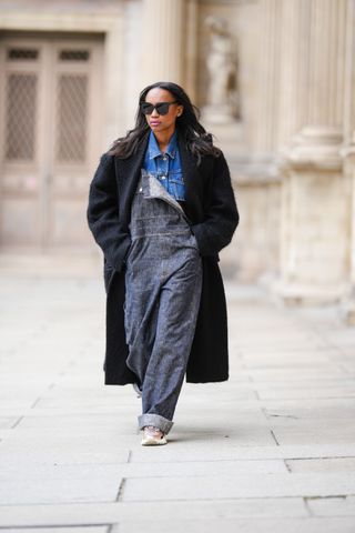 woman wearing overalls, a denim jacket, and a coat