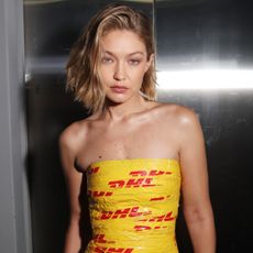 Gigi Hadid wearing a dhl tape dress backstage at the vetements show