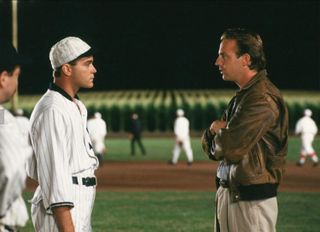 a young baseball player talks to his coach on a rural baseball field in field of dreams