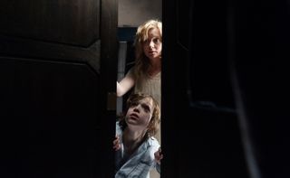 a mother and her son look through a crevice in The Babadook