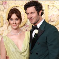 Leighton Meester wearing a lime green gown and Adam Brody wearing a green tux posing on Golden Globes 2025 red carpet