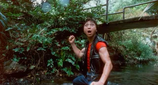 a man looks surprised walking through a river in the jungle in the movie miami connection