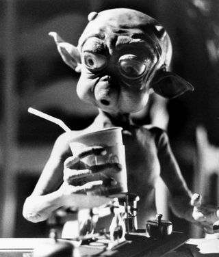 a little monster holding a cup of soda in the movie Mac and me