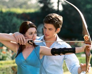 anne hathaway and chris pine hold a bow and arrow in a garden in the princess diaries 2