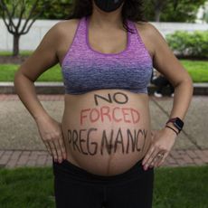 Pregnant woman with "no forced pregnancy" written on her belly