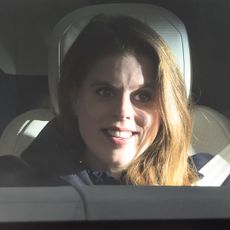 Princess Beatrice wearing a black coat riding in a car