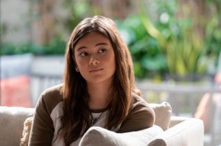 Lukita Maxwell as Alice, sitting on a couch in front of a glass patio wall, in 'Shrinking.'