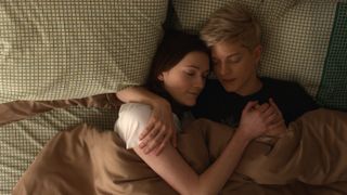 two women embrace while lying in bed together in the tv show Feel Good