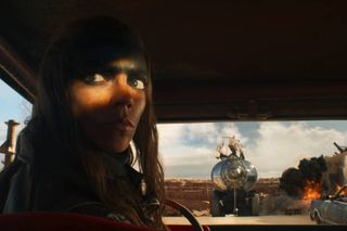 anya taylor joy with black makeup on her face driving a car in furiosa