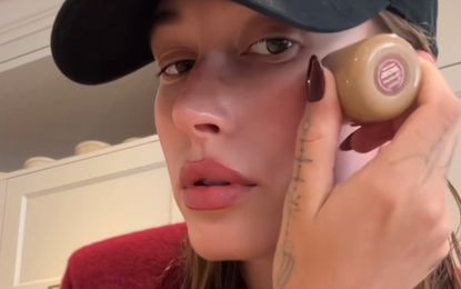 Hailey Bieber applying Rhode pocket blush while wearing a new wine red manicure