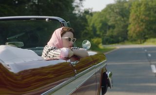 Midge Maisel riding in a car as she leans over the convertible edge in 'The Marvelous Mrs. Maisel'