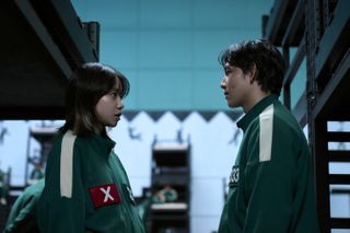 Jo Yu-ri and yim Si-wan wearing the player sweatsuits in squid game looking at each other by bunks