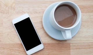 High Angle View Of Fresh Latte Served By Mobile Phone On Table