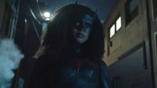 javicia leslie wears a bat mask and suit while walking through a dark street in Batwoman