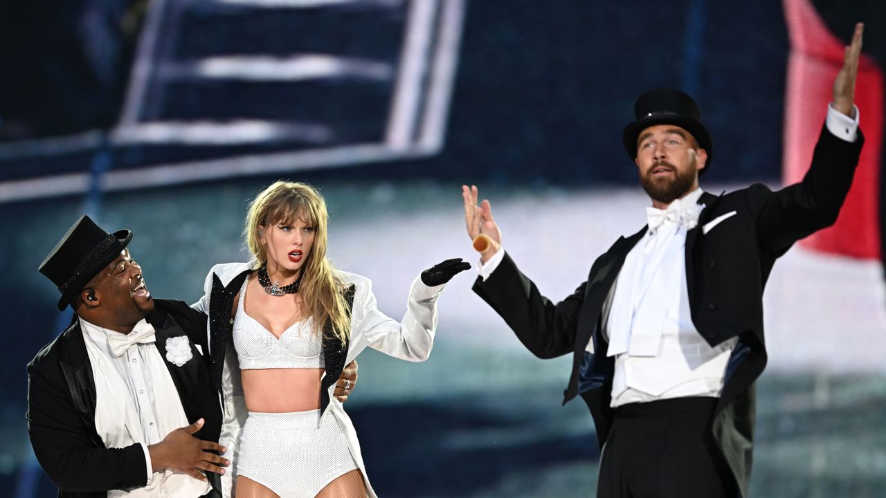 Taylor Swift and Travis Kelce on stage in black and white outfits during the Eras Tour